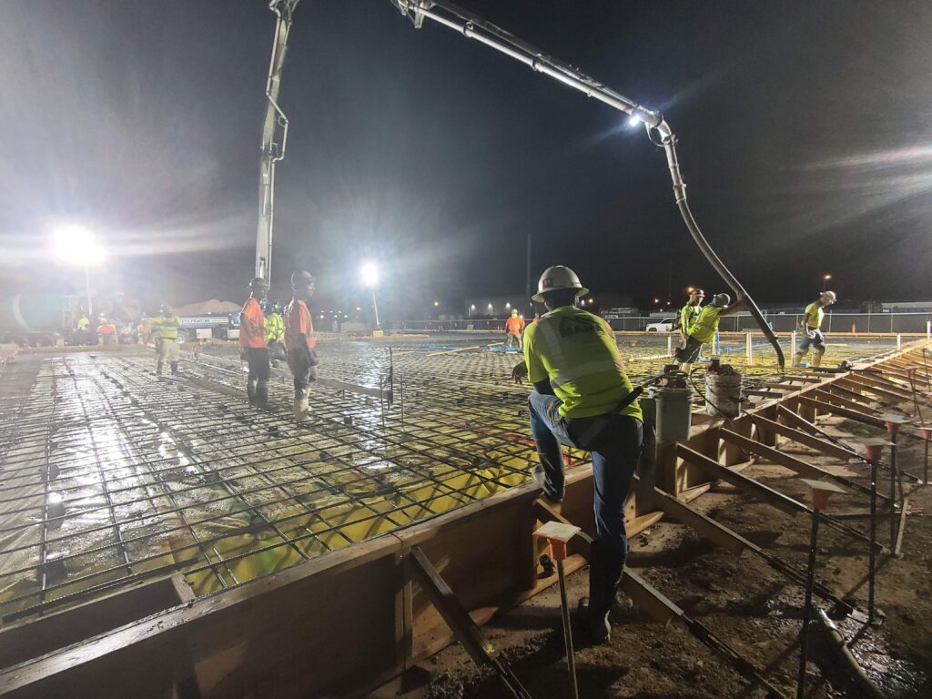 Crew placing concrete over a reinforced deck at night