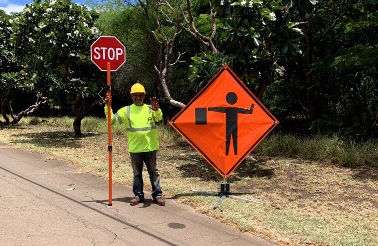 Mana flagger with a STOP paddle next to a flagger-ahead sign