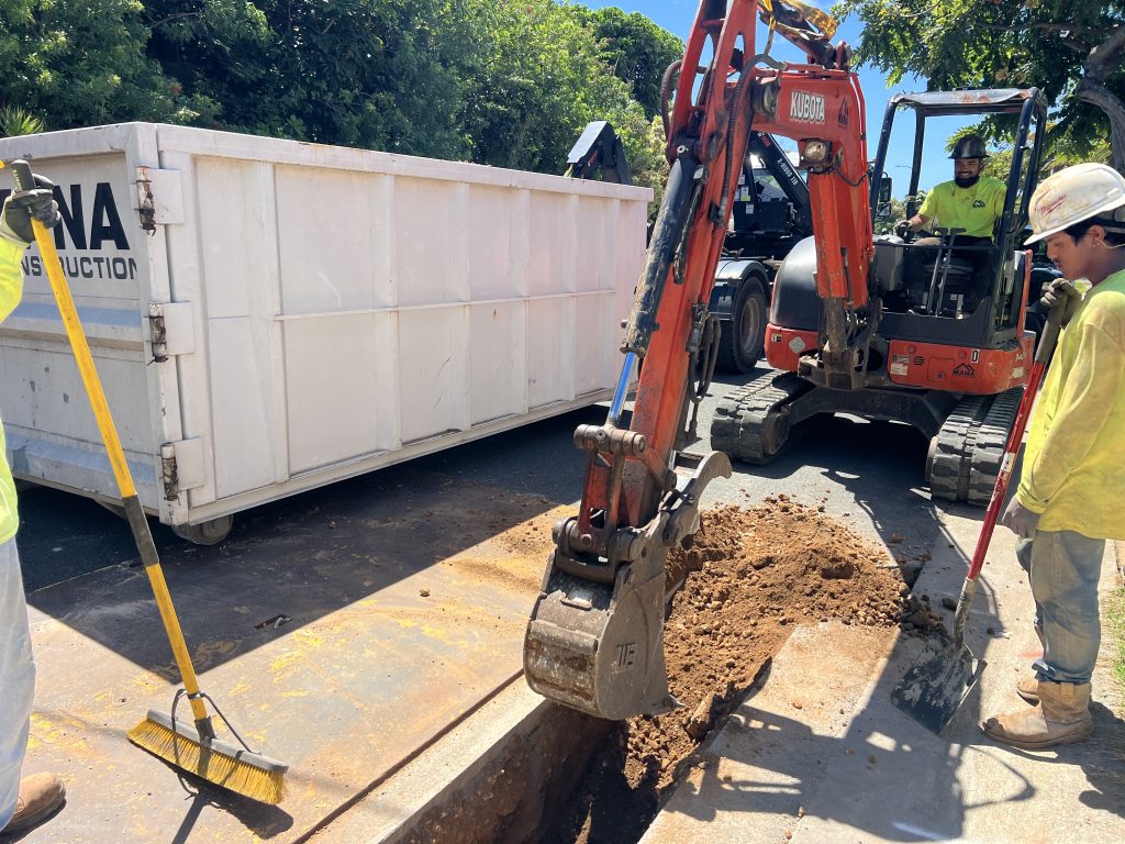Mana crew trenching with a mini excavator for underground utility work